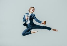woman in business suit and ballet shoes leaping