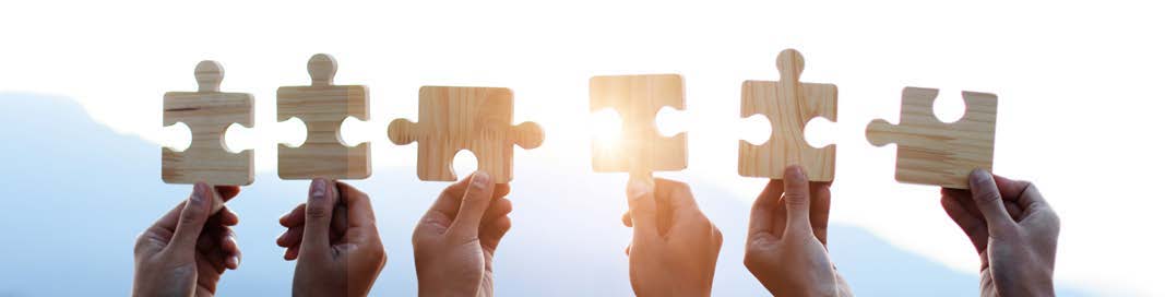 Hands holding wooden puzzle pieces together.