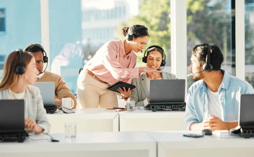 A contact center team collaborating at their computers.