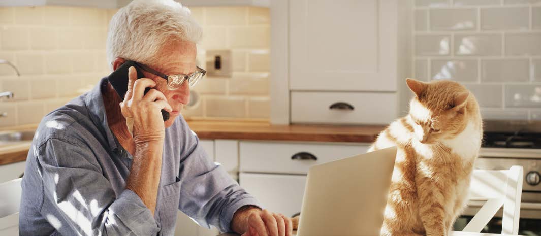A customer talking on the phone while using a laptop.